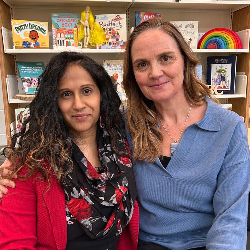 Kat and Nikki together smiling on a coach in the library